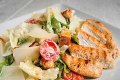 Hotelcamp Reinsehlen | Schneverdingen | Caesar Salad mit Hähnchenbrust, serviert auf einem weißen Teller.